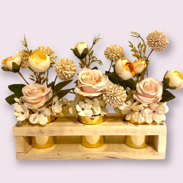 Pretty long life florals of pale pink roses, apricot ranunculas with small beige hydrangeas contained in three small votives encased in a handcrafted wooden case