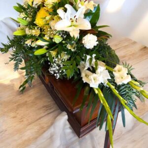 Yellow, white and green flowers and foilage suited to a casket.