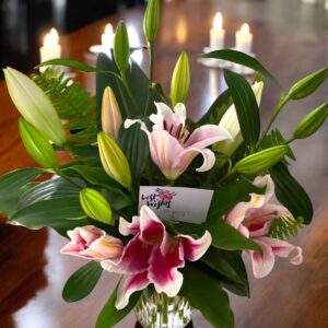 Beautiful large oriental dark and pink lilies with green leaves in a glass vase