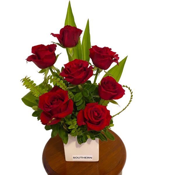 full size picture of red roses curled fern and green leaves in white cubed vase