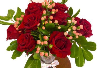 Eigh tdeep red roses in bloomwith pale pink berries with bold green leaves presented in a glass vase. Included are a valentine's day ribbon and heart notecard for your personal message.