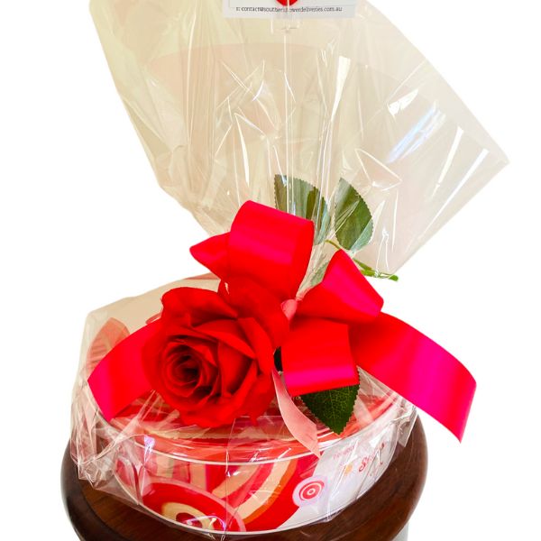 six hundred gram round tin of Cadbury assorted chocolates with clear cellophane and red rose and ribbon