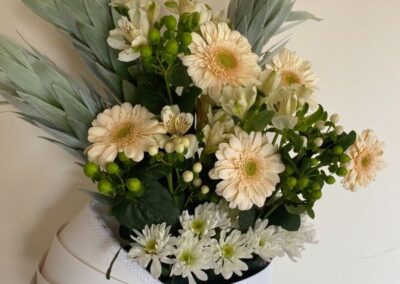 Arrival of a new baby flowers - gerberas, daisys, hypericum berries, silver tree stems in a white baby crib gift box