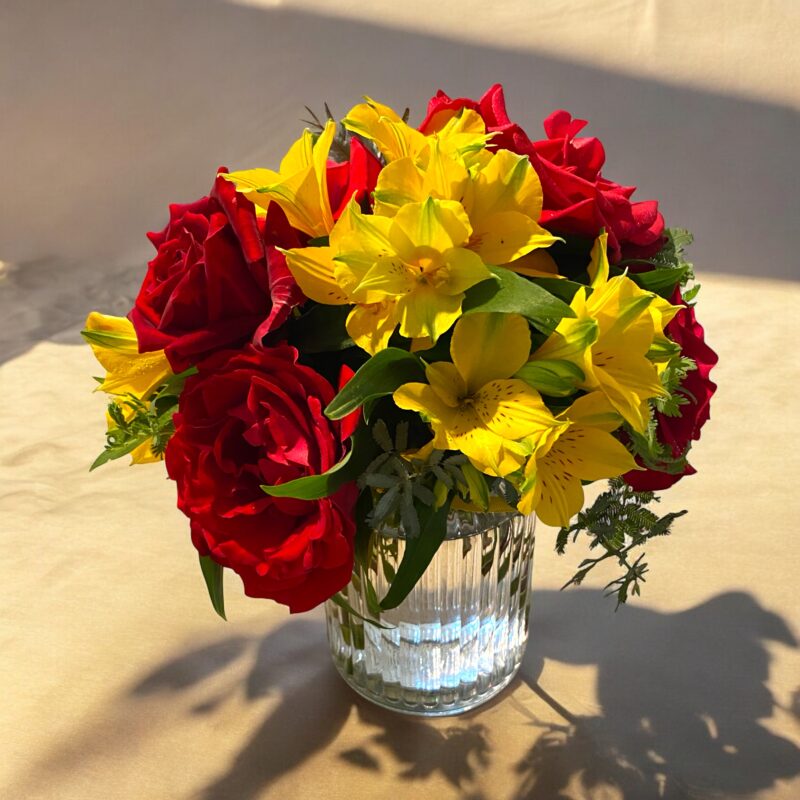 Red roses and yellow alstromeria in glass vase