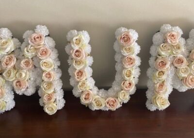 Mum in three seperate letters, artificial white flowers with apricot pastel roses approximately fifty centimetres in height